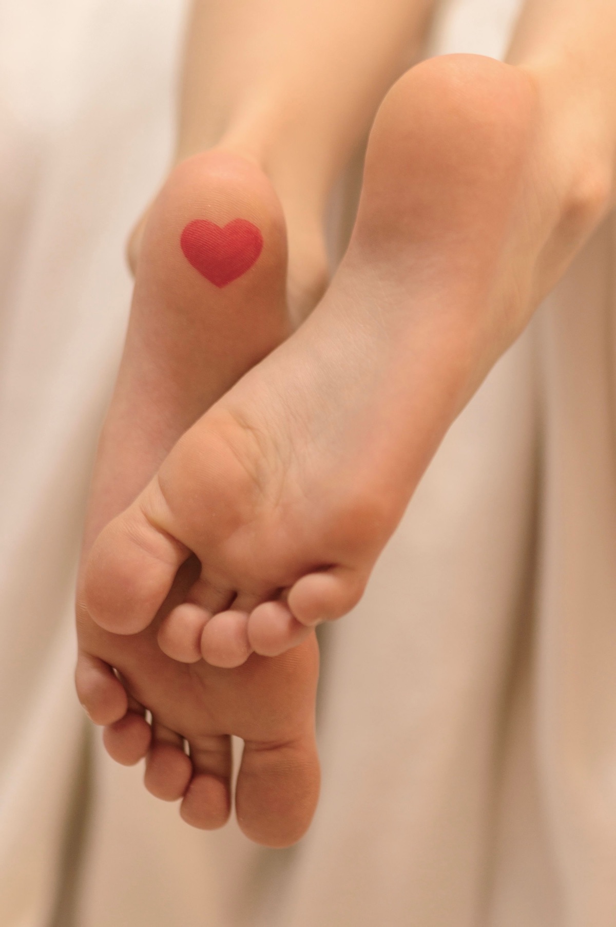 Bare soles with a small red heart drawn on one foot